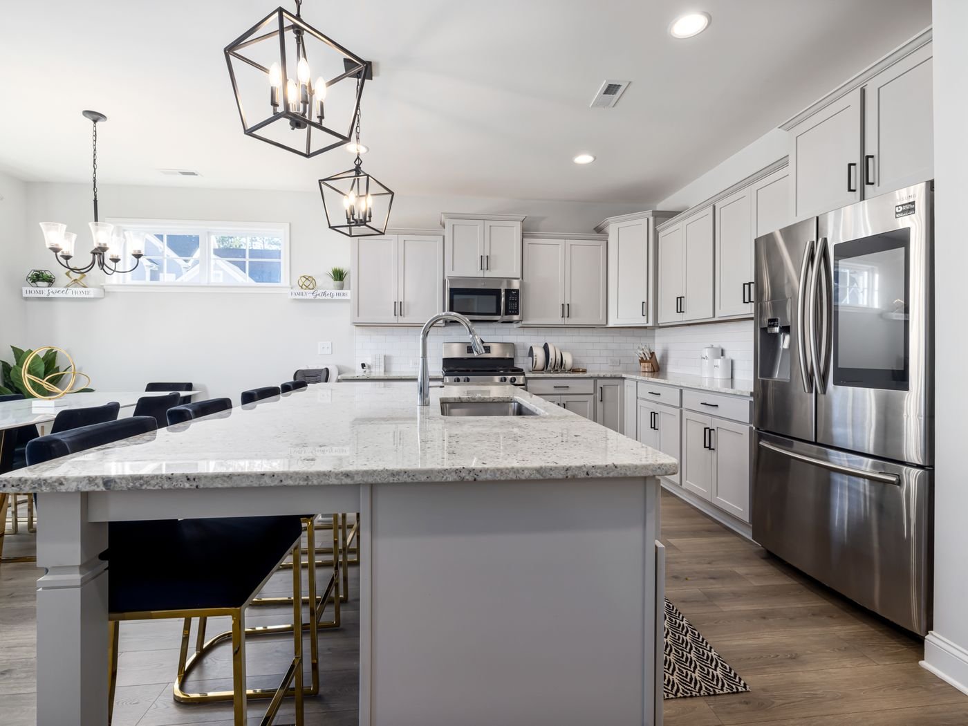Bright contemporary kitchen with white cabinetry, island seating, and layered lighting